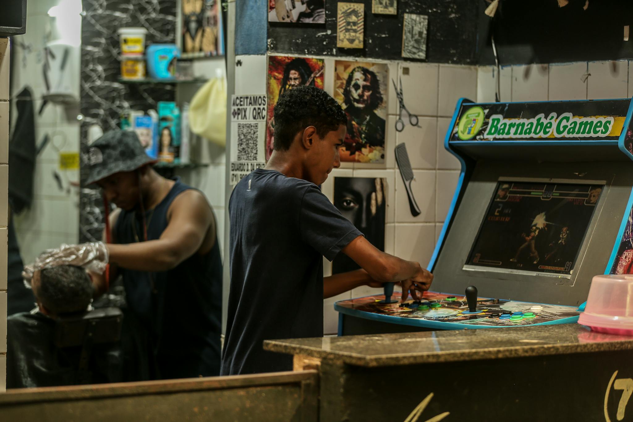 Youth playing arcade game in a lively barbershop setting capturing urban culture.